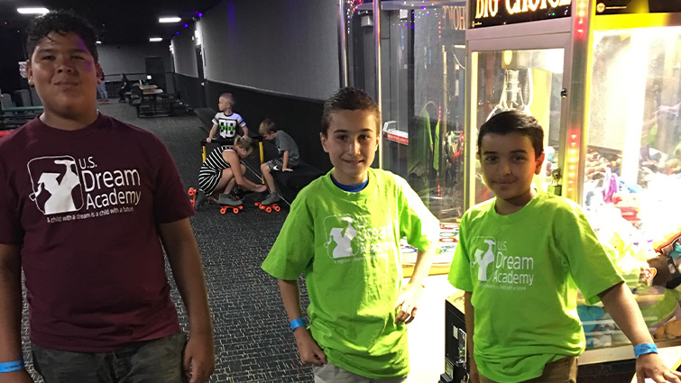 2 kids and a teenager next to an arcade game in a roller rink