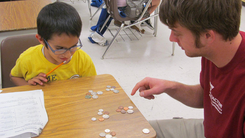 Image of young-adult mentor teaching young boy
