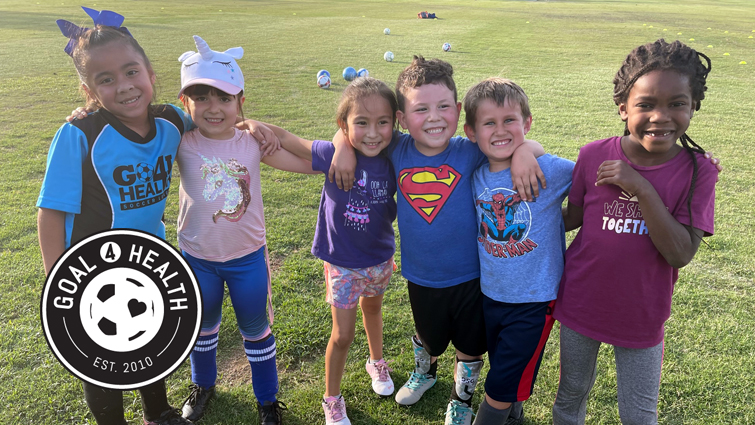 children in soccer cleats smiling at camera