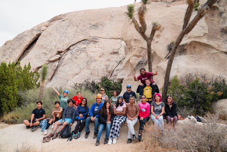 students posed for a picture on some rocks and brush