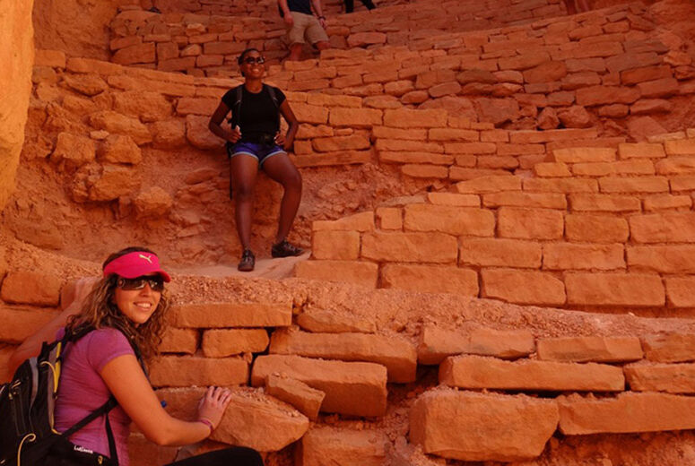 students on field trip climbing hillside with bricks